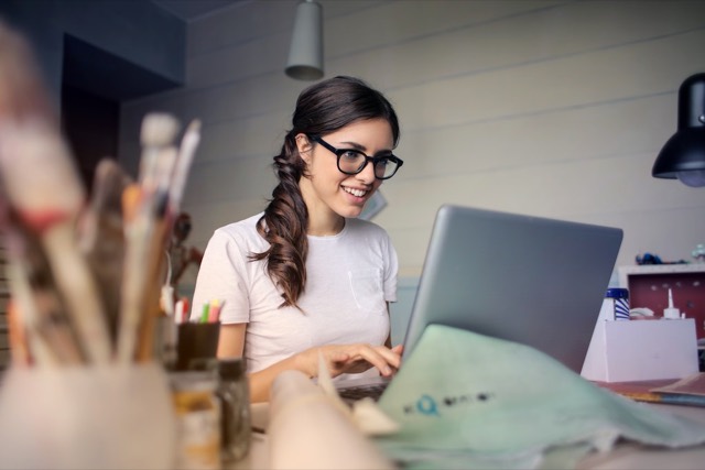 Lachende vrouw met bril achter een laptop