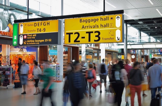 Drukke vertrekhal van een luchthaven met borden naar de terminals